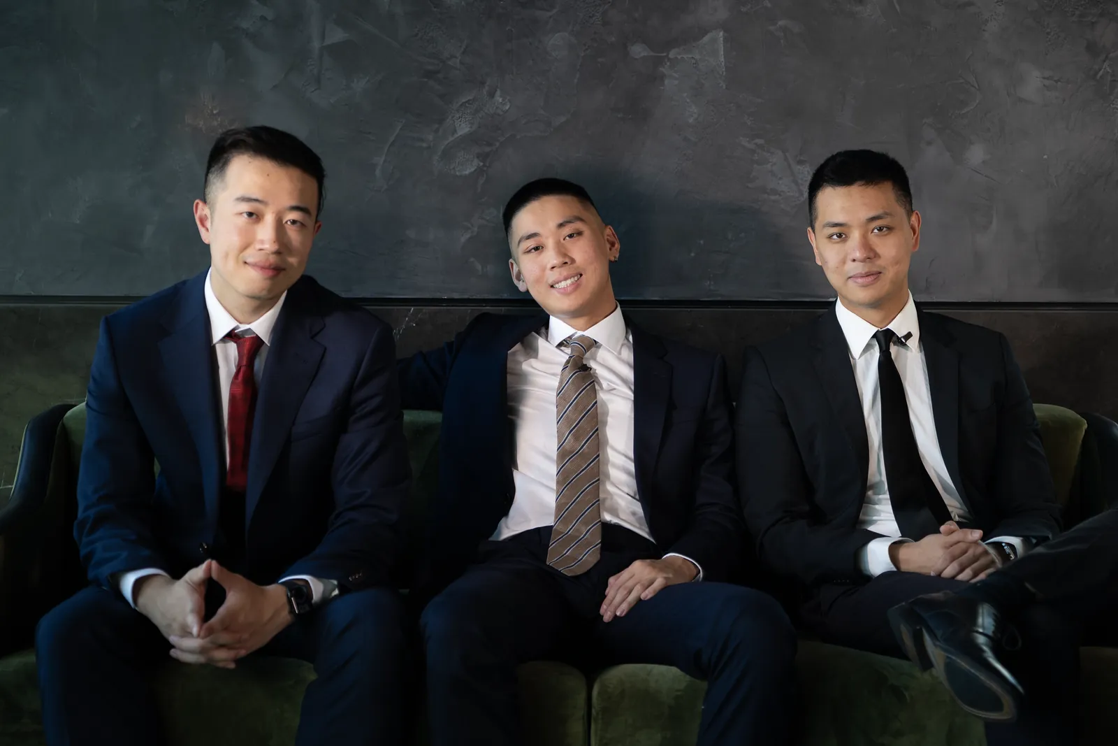 Terence Mok, Jordan Pham and Stanley Ma in suits on a green velvet sofa